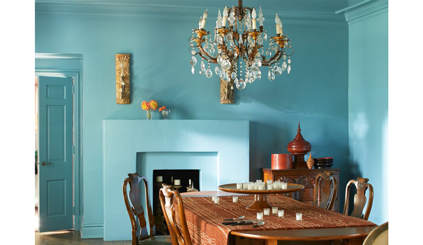 Comedor opulento azul con lámpara de araña, mesa y sillas de madera. Clásico con toque exótico