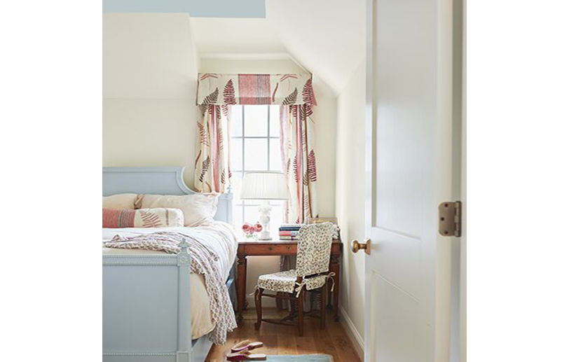 Dormitorio crema, techo celeste, cama azul y cortinas y cojines rosados.