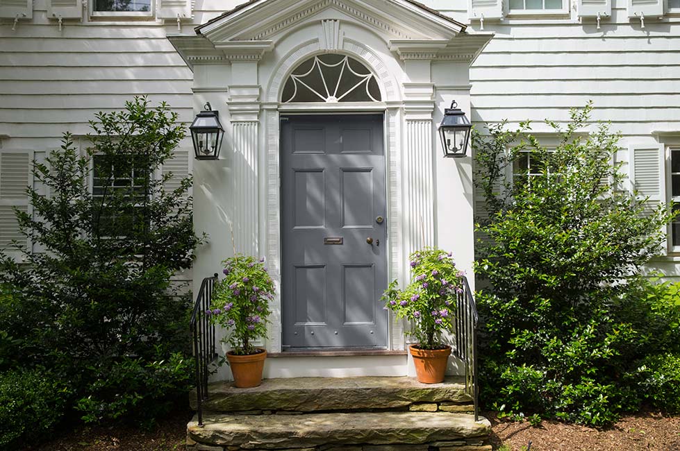 Una entrada frontal de estilo colonial con una puerta principal pintada de gris