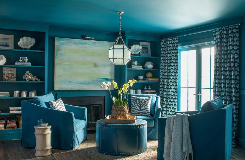 Una sala de estar pintada completamente de azul con sillones de club azules y estanterías empotradas