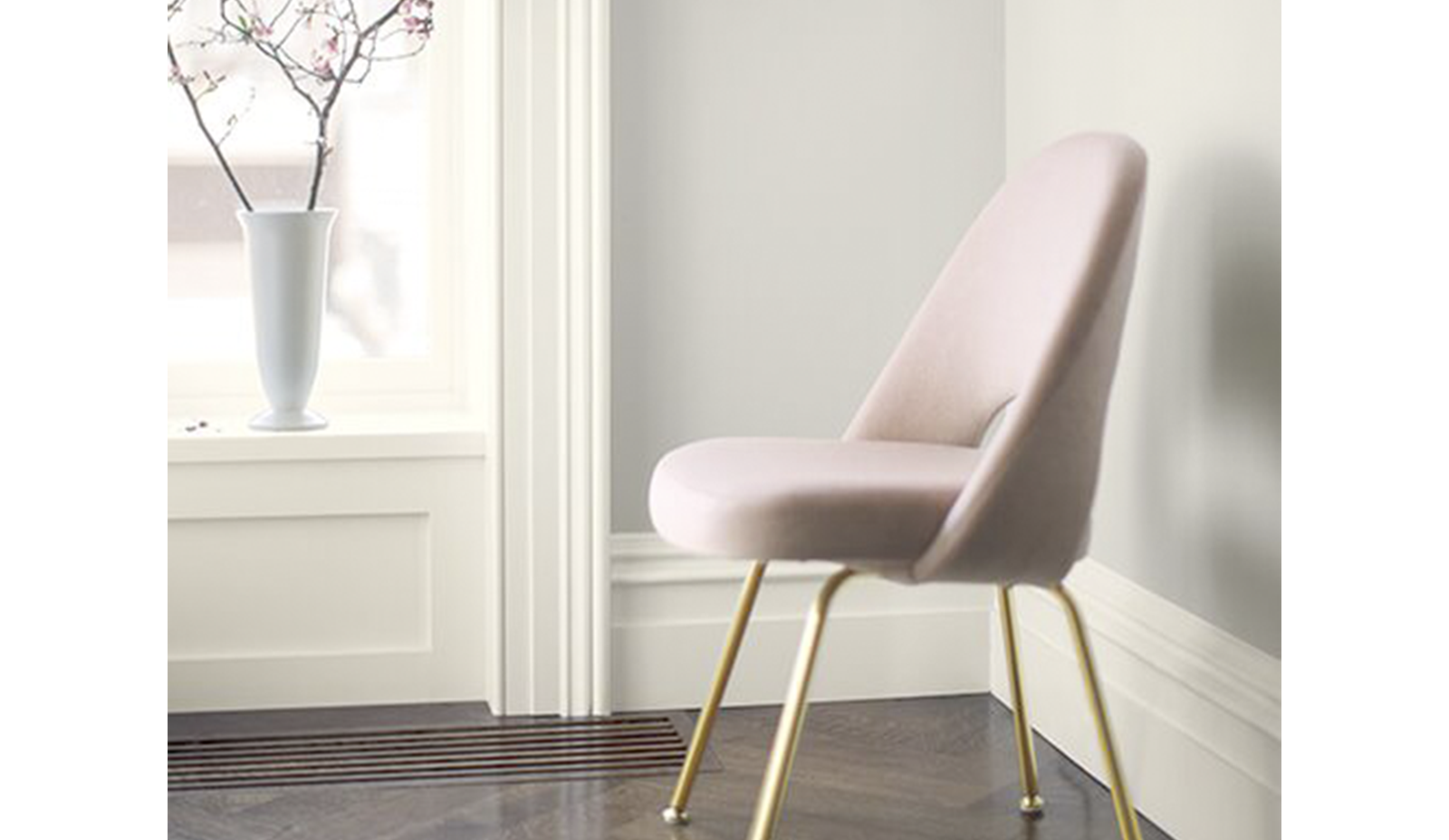 Una silla rosa enmarca una pared pintada en Balboa Mist OC-27.