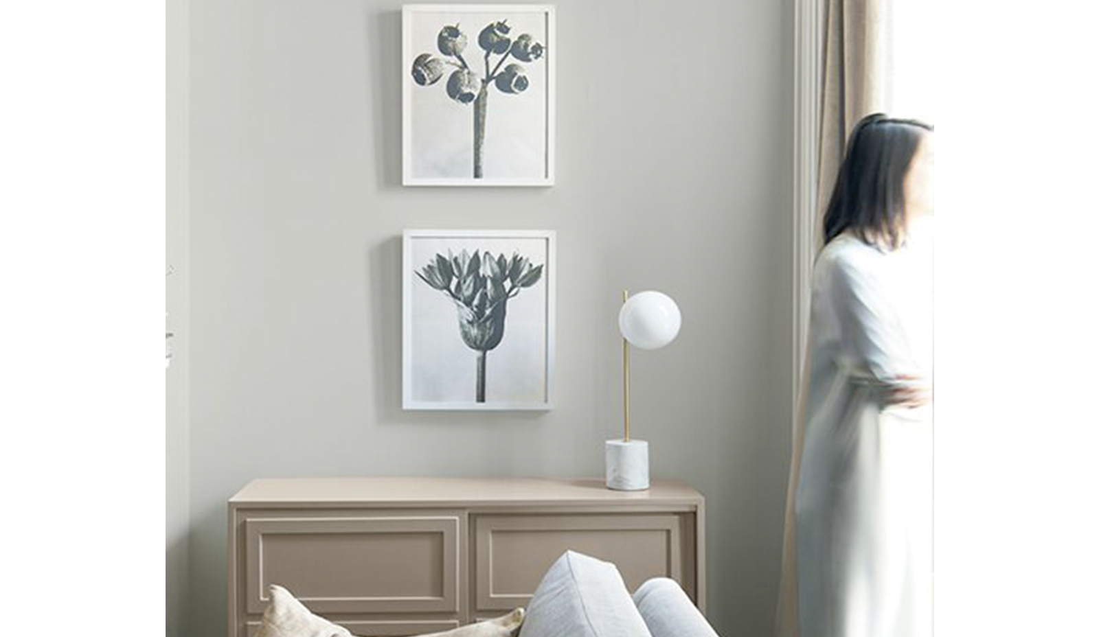 Salón gris claro con dos marcos colgados sobre un mueble de madera junto a un sofá gris.