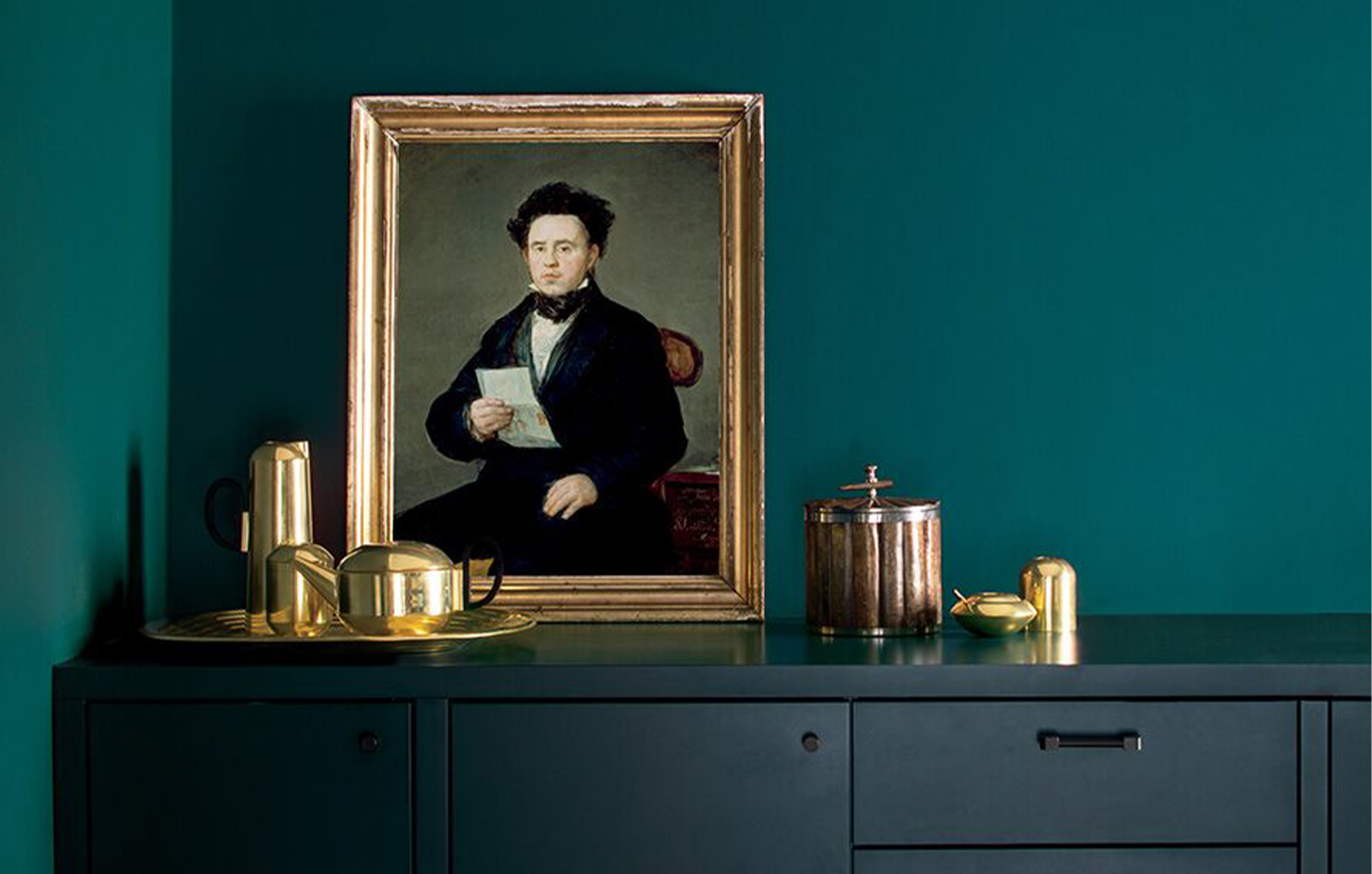 Un comedor con paredes verdes y un gabinete azul marino, con un retrato en un marco dorado