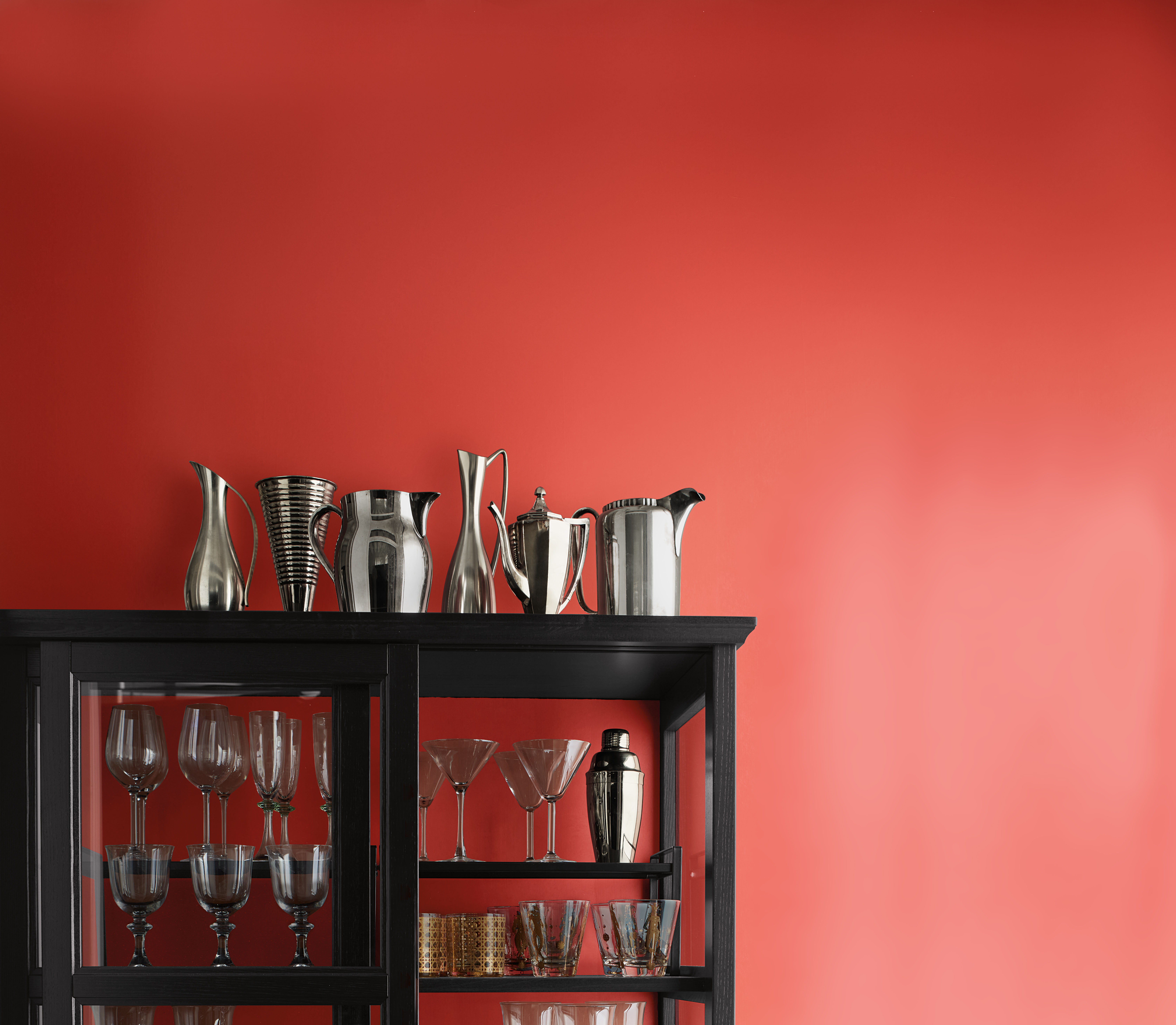 Gabinete de jarras pintado de negro con varios vasos en los estantes frente a Raspberry Blush