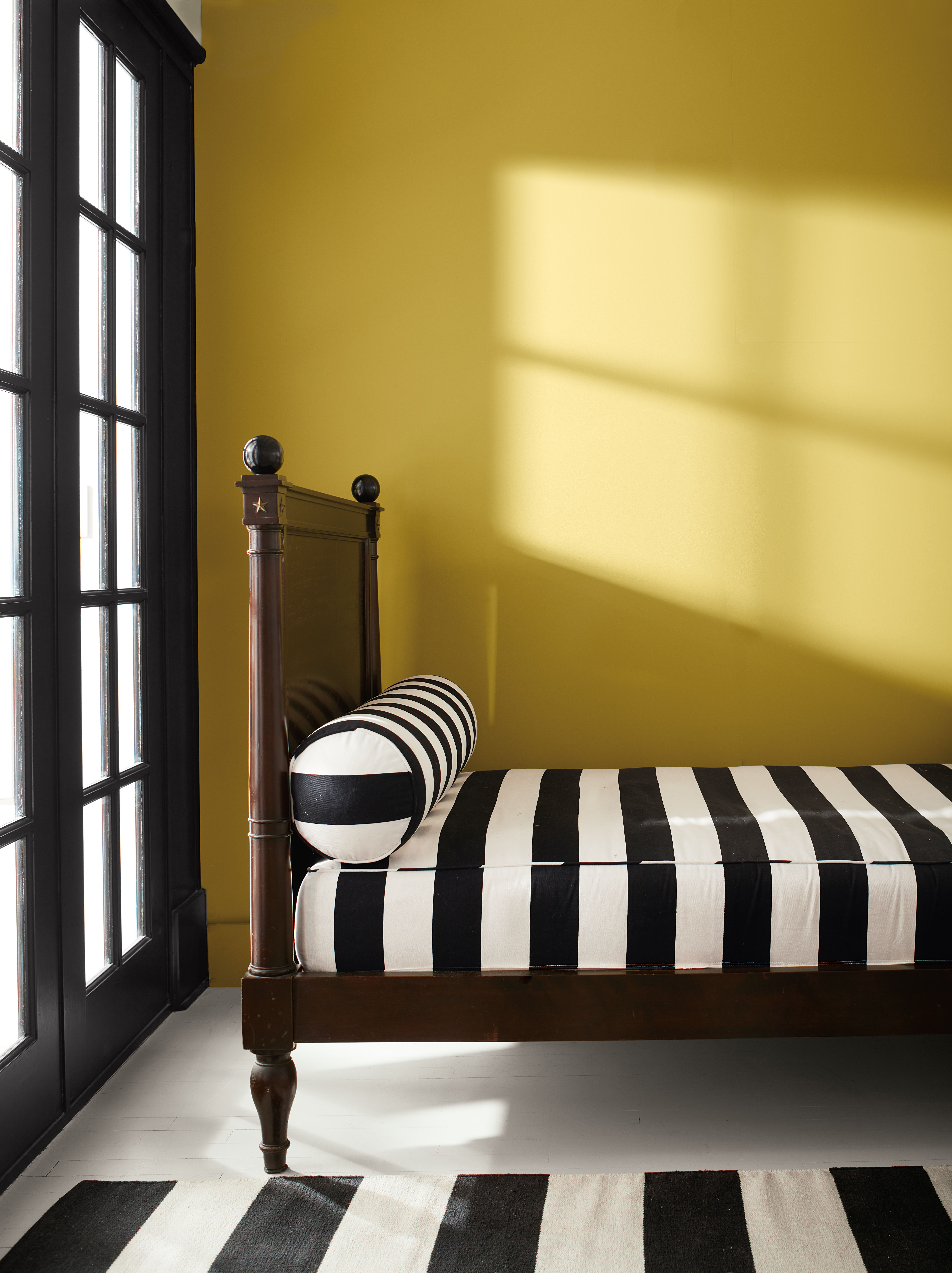 Dormitorio pintado de Savannah Green con puertas de color Onyx, cama de madera y suelo blanco.